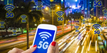 Digital composite of 5G , a woman hand using smartphone with blurry modern city on the background. Hong Kong busy city and High speed mobile web technology concept.