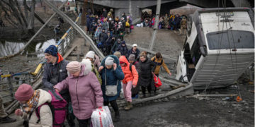 Фото: People cross on an improvised path under a bridge that was destroyed by a Russian airstrike, while fleeing the town of Irpin, near Kyiv. (Vadim Ghirda/AP)