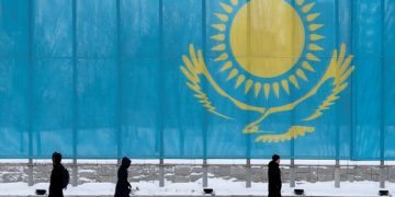 FILE PHOTO: People walk past a gaint Kazakhstan flag in Astana, Kazakhstan March 5, 2019.  REUTERS/Pavel Mikheyev/File Photo