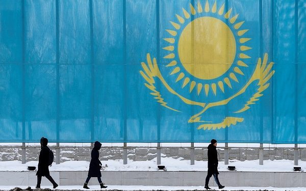 FILE PHOTO: People walk past a gaint Kazakhstan flag in Astana, Kazakhstan March 5, 2019.  REUTERS/Pavel Mikheyev/File Photo