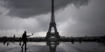 A man takes pictures as he enjoys the scenery of the Eiffel Tower from Trocadero after a rain shower in Paris on August 10, 2017. / AFP PHOTO / PHILIPPE LOPEZ