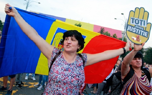 epa06829198 Women shout slogans and hold a Romanian flag (L) and a banner reading 'All for Justice' during a protest in front of Victoria palace, government headquarters, in Bucharest, Romania, 21 June 2018. Thousands of people gathered to protest against the changes to the judiciary system pushed in parliament by the leftist ruling party Social Democracy Party (PSD). The opposition parties and civil right activists are saying that these revisions to anti-corruption laws are means to increase political control over the judiciary and to limit the independence of judges and prosecutors.  EPA-EFE/BOGDAN CRISTEL