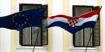 epa03757462 A Croatian national flag (R) and a European Union flag (L) fly side by side in front of the government building in Zagreb, Croatia, 24 June 2013. Following the successful ratification of its European Union Accession Treaty by the national parliaments of the 27 member states, the Republic of Croatia is set to join the European Union as the organization's 28th member on 01 July 2013.  EPA/ANTONIO BAT