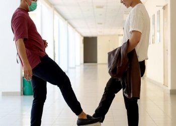 Two young men are tapping their shoes as alternative to handshakes.