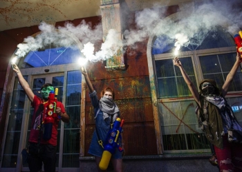 Protesters light flares after they spray paint the facade of the Ministry of Justice building, during an anti-government protest in Skopje on May 31, 2016, in a series of protests dubbed Colorful Revolution. President Gjorge Ivanov on Friday said he had partially retracted his controversial pardons of 56 persons, which has sparked mass protests and worsened Macedonia's political crisis. / AFP PHOTO / Robert ATANASOVSKI
