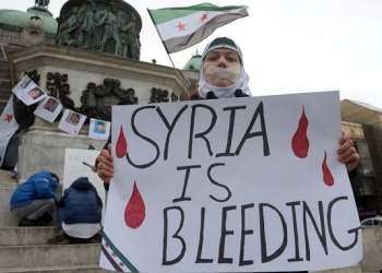 A Syrian living in Serbia displays a placard on March 16, 2013 during a protest against Syria's President Bashar al-Assad in the center of Belgrade.  AFP PHOTO / ALEXA STANKOVIC        (Photo credit should read ALEXA STANKOVIC/AFP/Getty Images)