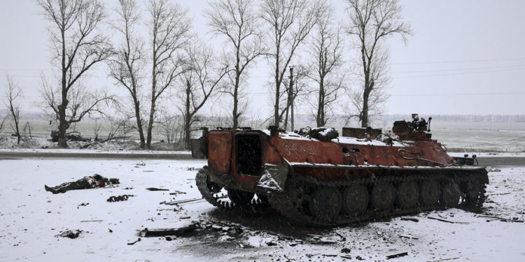 epa09784974 A soldier's lifeless body (L) lies next to a burnt Russian APC after the Ukrainian army attacked it the previous day near the city of Kharkiv, Ukraine, 25 February 2022. Russian troops entered Ukraine on 24 February prompting the country's president to declare martial law and triggering a series of announcements by Western countries to impose severe economic sanctions on Russia.  EPA-EFE/SERGEY KOZLOV