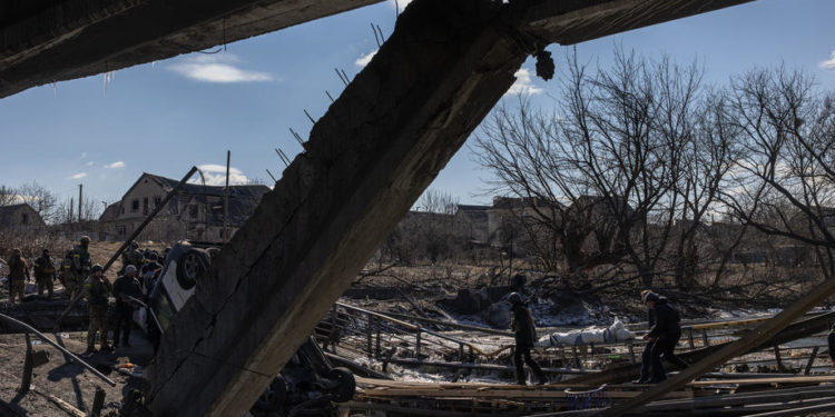 epa09815737 A police officer and a man carry on a destroyed bridge the dead body of a woman, who was allegedly killed by the Russian army, as residents flee from the frontline town of Irpin, Kyiv (Kiev) region, Ukraine, 10 March 2022. Thousands of residents are feeling Irpin and Bucha, as well as other settlements near Kyiv which were the most affected by the Russian army invasion.  EPA-EFE/ROMAN PILIPEY
